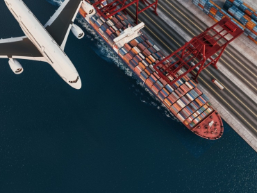 A,Cargo,Ship,At,The,Port,With,A,Flying,Airplane,