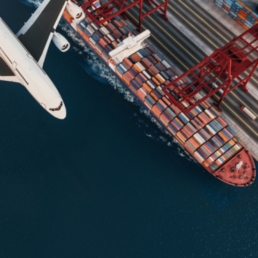 A,Cargo,Ship,At,The,Port,With,A,Flying,Airplane,